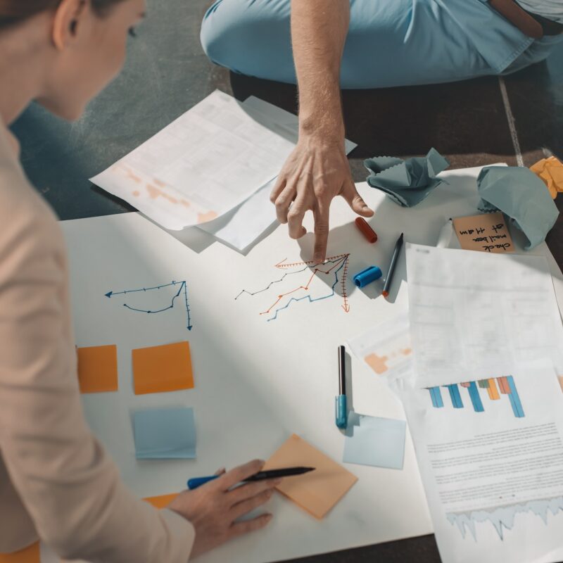 Young business people sitting on floor and working with charts