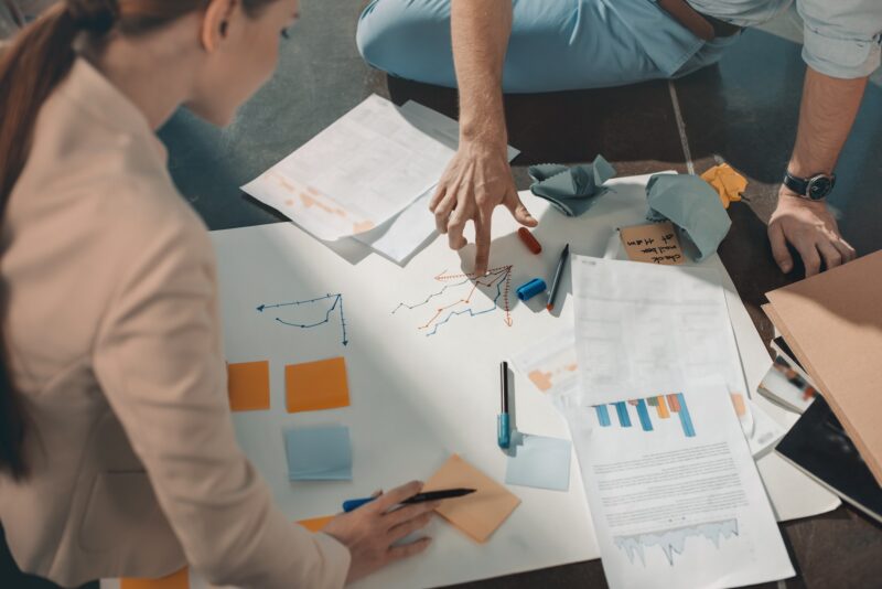 Young business people sitting on floor and working with charts