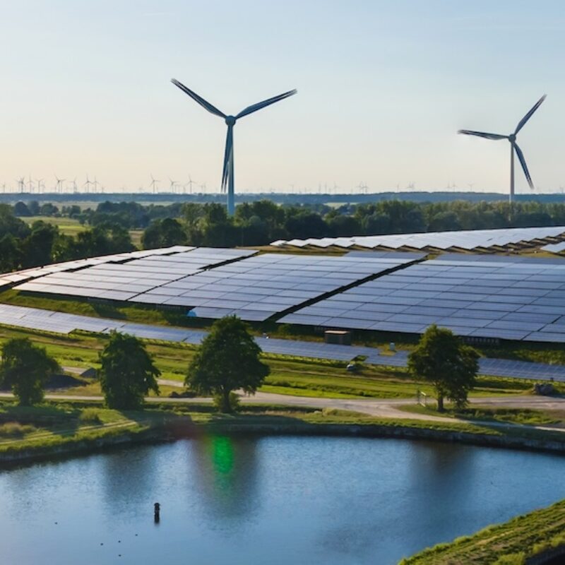 Environmentally friendly installation of photovoltaic power plant and wind turbine farm situated by landfill.Solar panels farm built on a waste dump and wind turbine farm. Renewable energy source.