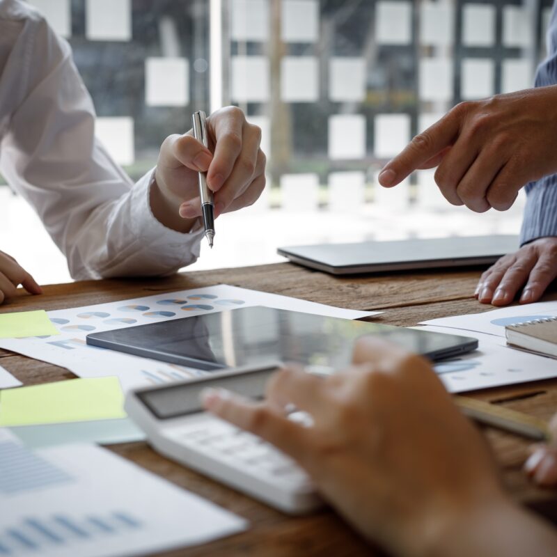 Financial analysts analyze business financial reports on a digital tablet planning investment project during a discussion at a meeting of corporate showing the results of their successful teamwork.