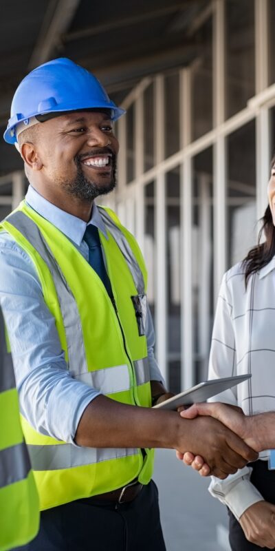 Smiling,Engineer,Shaking,Hands,At,Construction,Site,With,Happy,Architect.