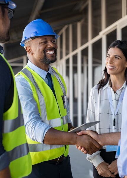 Smiling,Engineer,Shaking,Hands,At,Construction,Site,With,Happy,Architect.